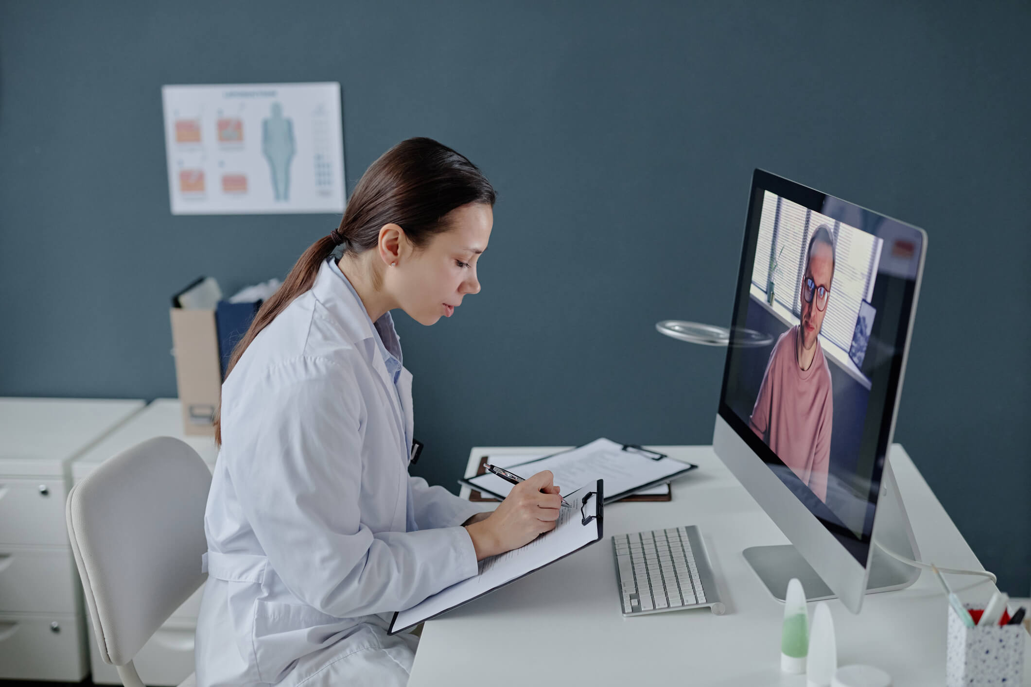 Doctor taking notes during virtual consultation